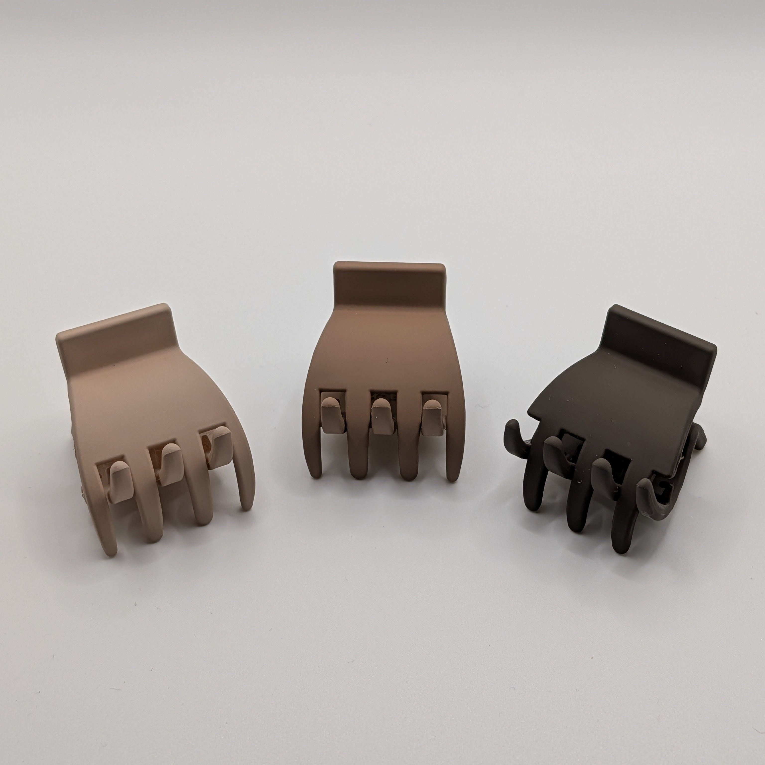 Top-down view of a 3-piece set of matte plastic hair claw clips in light to dark brown.

Ansicht von oben auf ein 3er-Set matter Kunststoff-Haarklammern in Hell- bis Dunkelbraun.