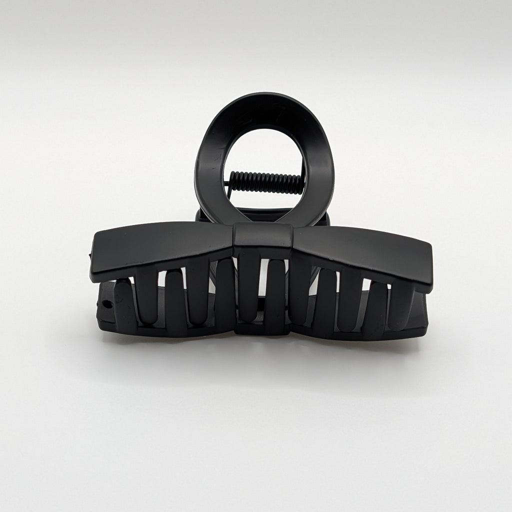 Front perspective of a black matte bow-tie hair claw clip with strong teeth.

Frontalansicht einer schwarzen matten Schleifen-Haarklammer mit starken Zähnen.