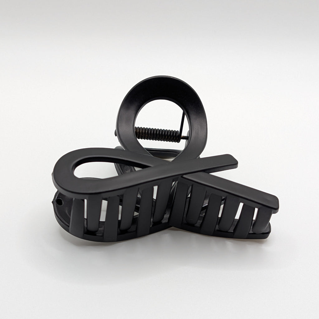 Matt Schwarz - Angled view of a matte black infinity loop design hair claw clip.	

Schrägansicht einer mattschwarzen Haarklammer im Unendlichkeits-Loop-Design.