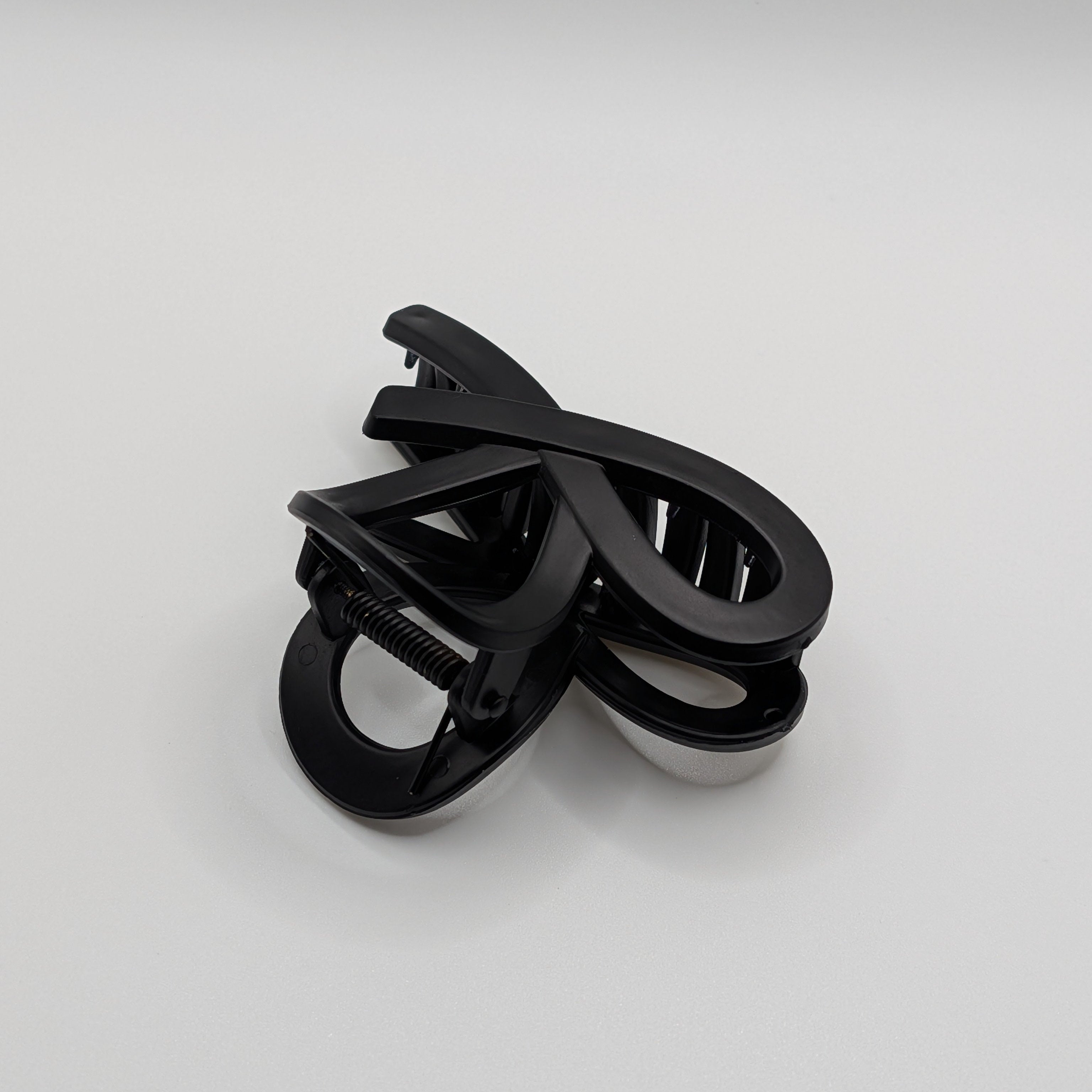 Matt Schwarz - Close up of the matte black infinity loop claw clip showing the metal spring.

Nahaufnahme der mattschwarzen Unendlichkeits-Haarklammer mit sichtbarer Metallfeder.