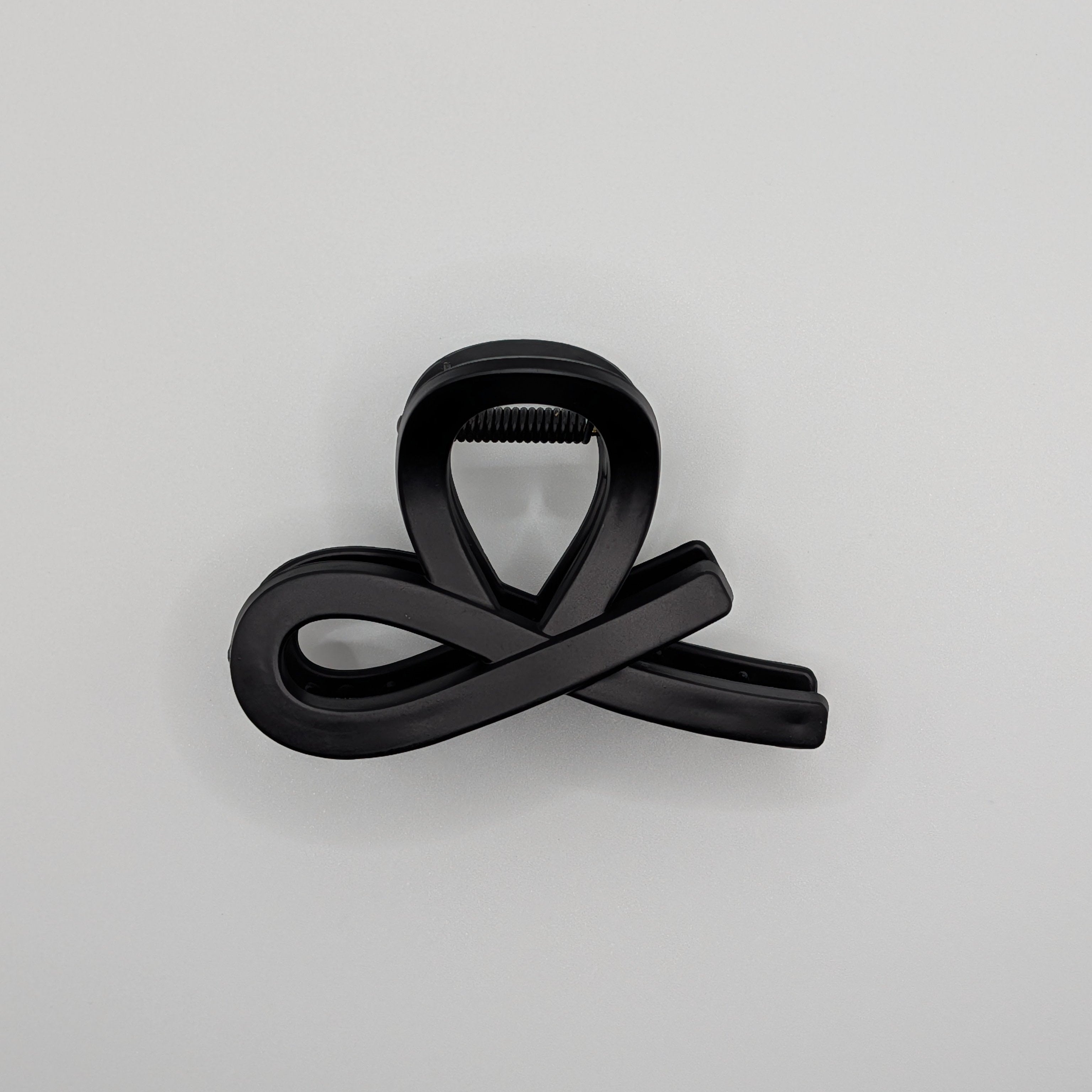 Matt Schwarz - Side view of a minimalist black infinity loop hair clip on a white background.	

Seitenansicht einer minimalistischen schwarzen Unendlichkeits-Haarklammer auf weißem Hintergrund.