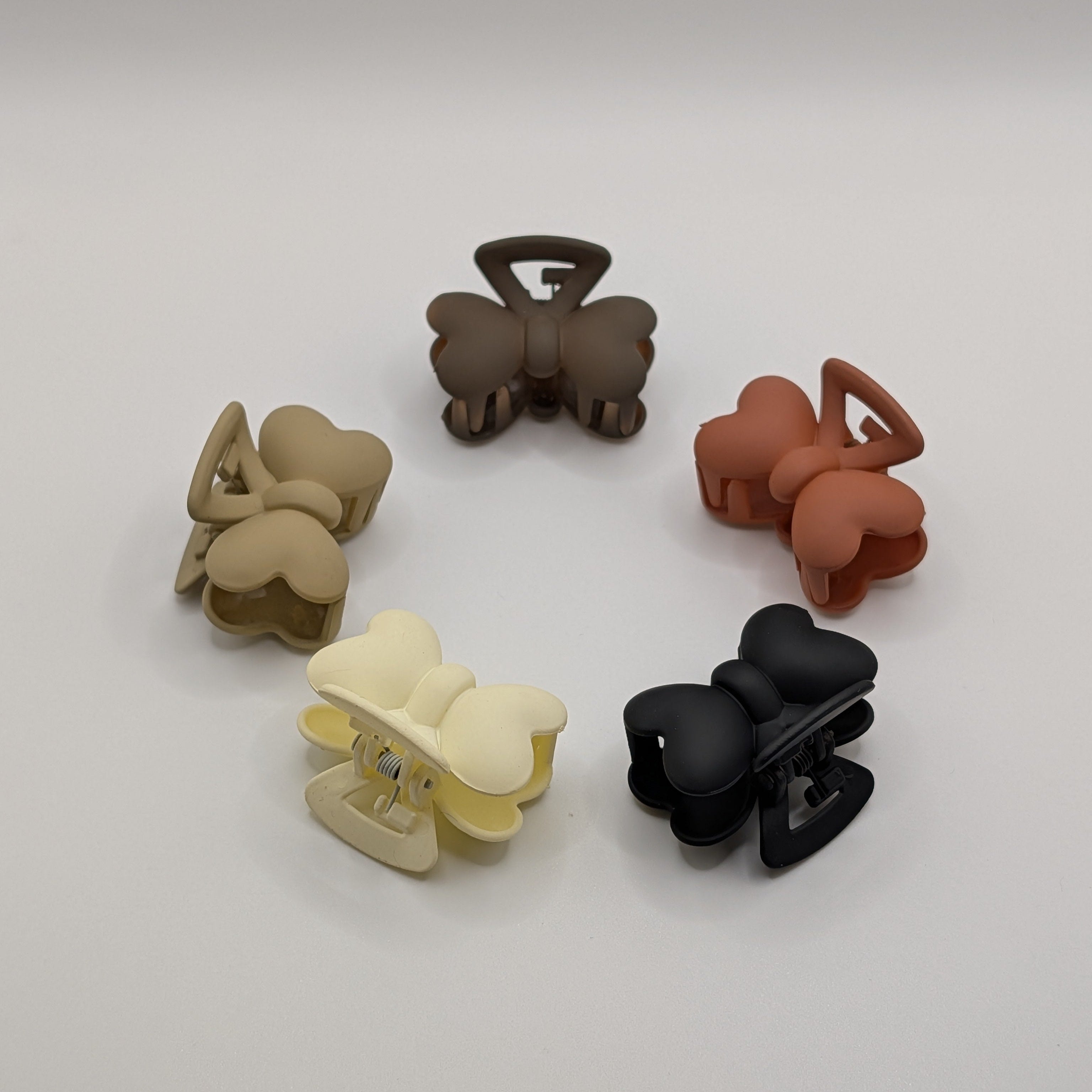 Top-down view of five 4cm butterfly bow hair clips arranged in a circle on a white surface.

Fünf 4 cm große Schmetterlings-Haarclips, kreisförmig auf weißem Untergrund angeordnet.