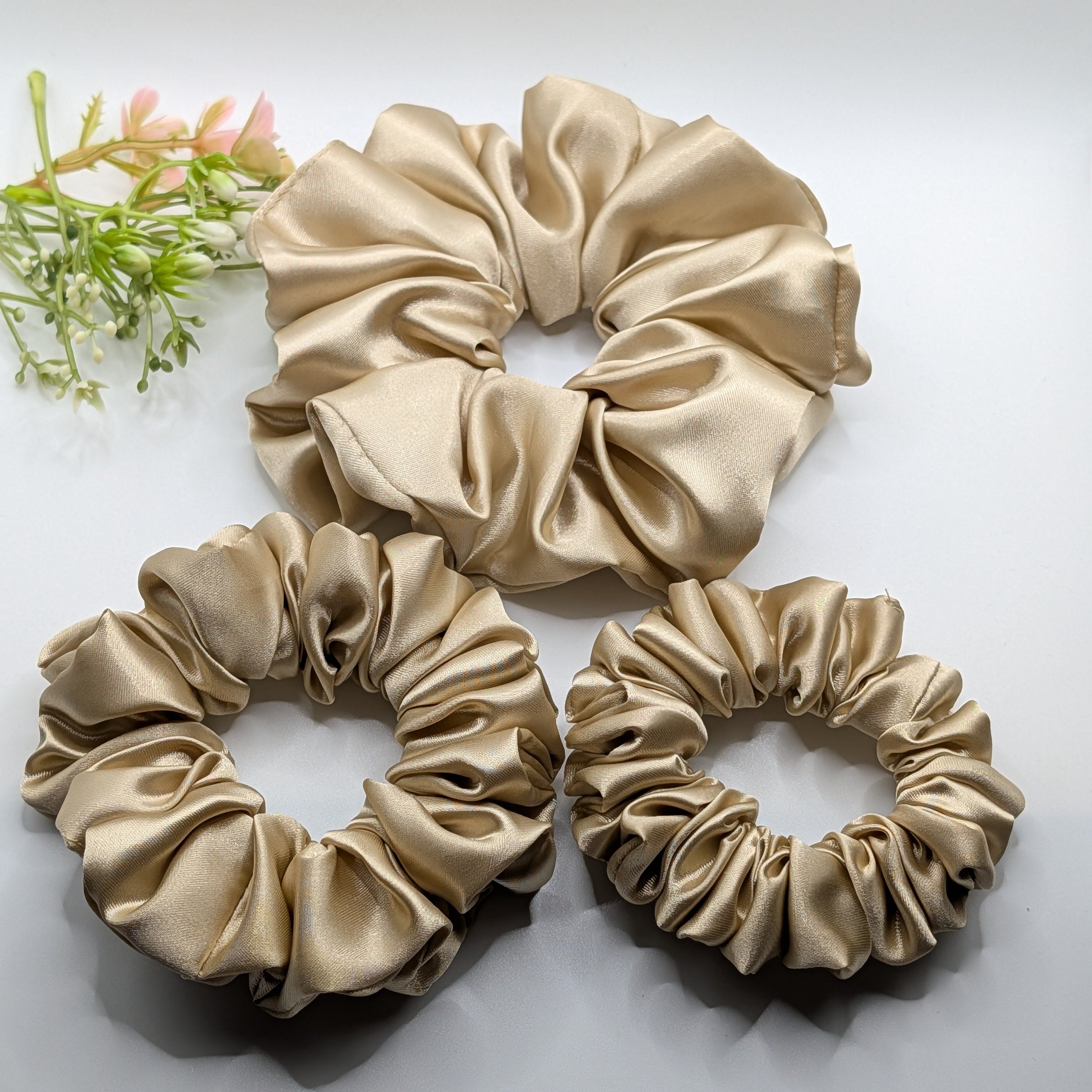3er Set - Set of 3 champagne gold satin scrunchies in large, medium, and small sizes.

3er-Set Satin-Haargummis in Champagner-Gold (Groß, Mittel, Klein).