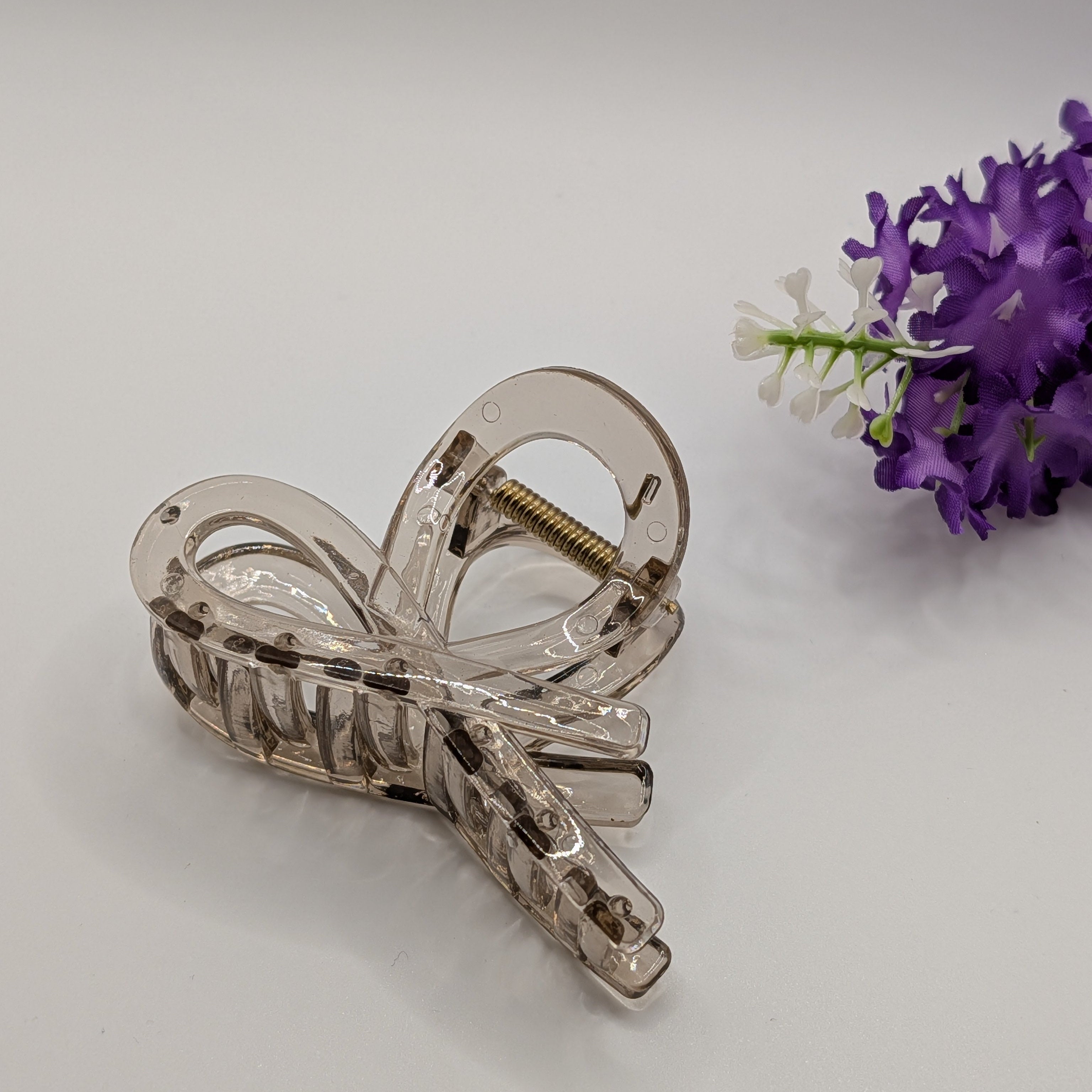 Transparent - Crystal clear bow hair clip displayed with purple flowers for an aesthetic look.

Kristallklare Haarschleifen-Klammer präsentiert mit lila Blumen für einen ästhetischen Look.