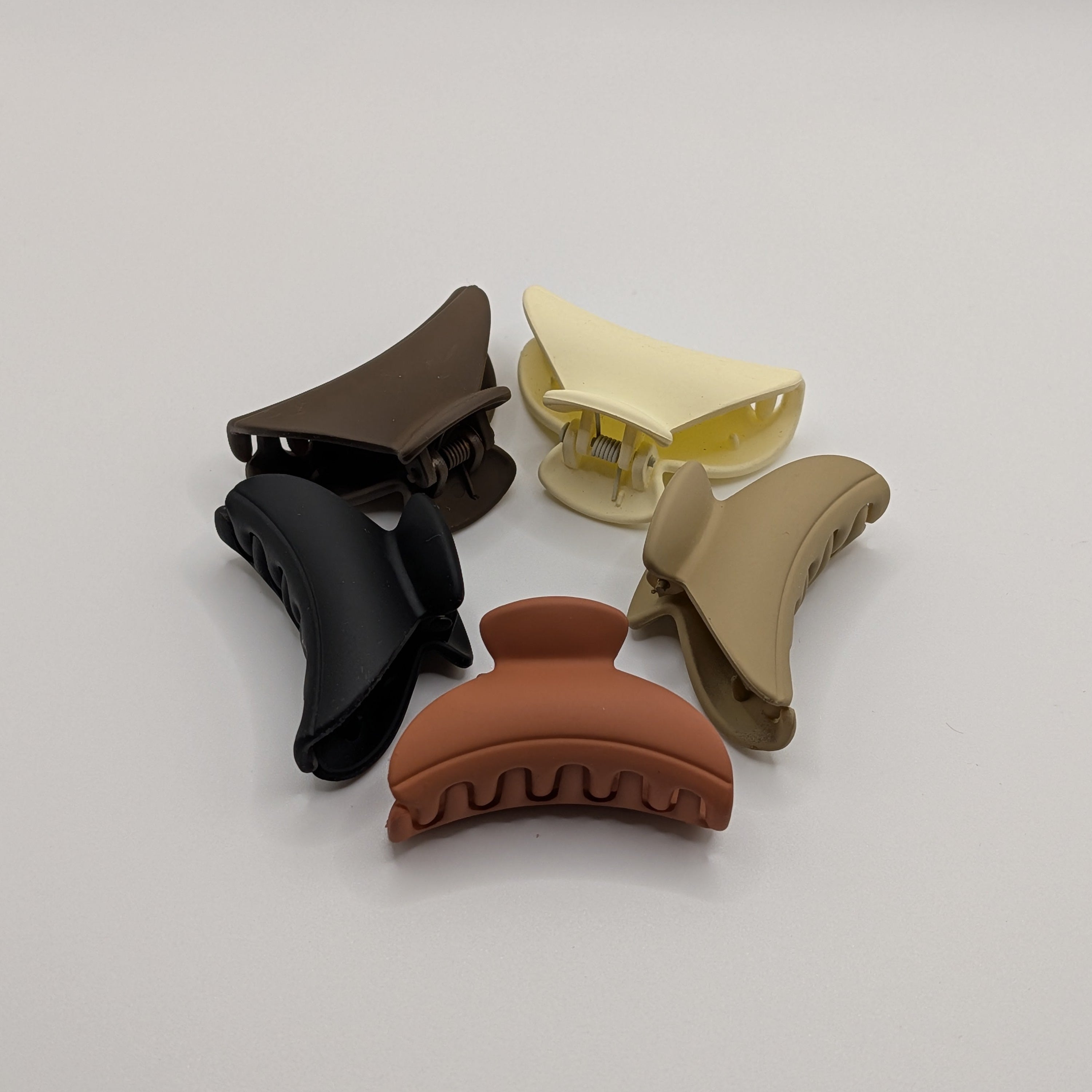 Close-up of clustered matte hair clips highlighting the terracotta and cream colors.

Nahaufnahme von matten Haarklammern in Terrakotta und Creme.