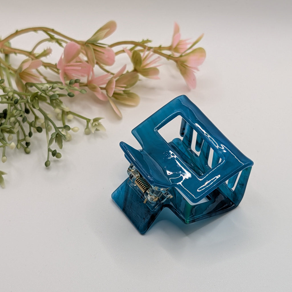 Ozeanblau Marmoriert - Haarspange „Geo-Marine“ | Transluzentes Petrol-Blau - Mercy Haaraccessoires

Eine petrolfarbene, eckige Haarklammer aus Acryl, schräg von oben fotografiert mit Blumen im Hintergrund.