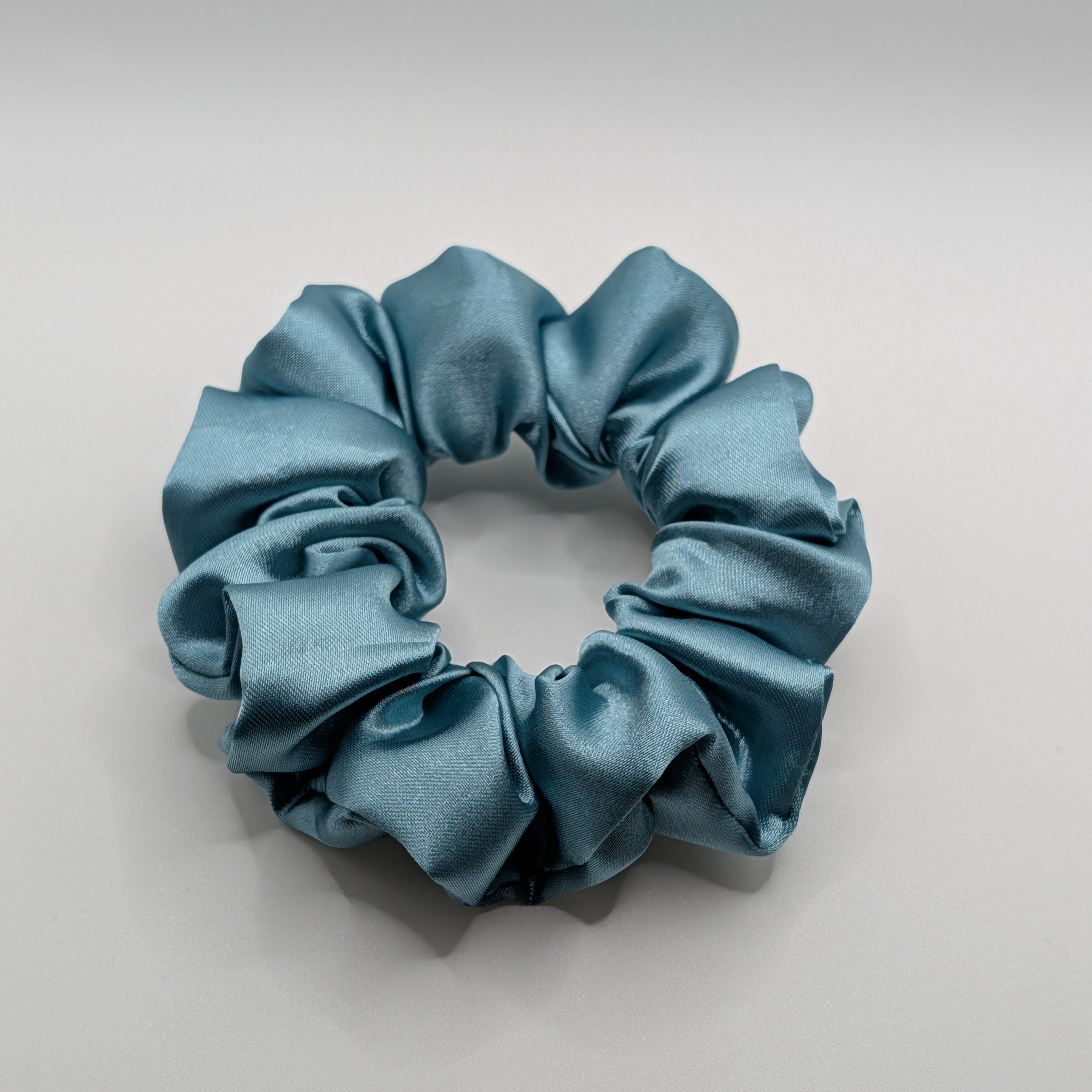 mittel - Durable blue satin scrunchie ideal for thick or curly hair.	

Langlebiges blaues Satin-Haargummi, ideal für dickes oder lockiges Haar.