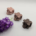 Three matte floral hair clips arranged next to purple flowers on a clean white surface.

Drei matte florale Haarklammern, arrangiert neben lila Blumen auf einer sauberen weißen Fläche.