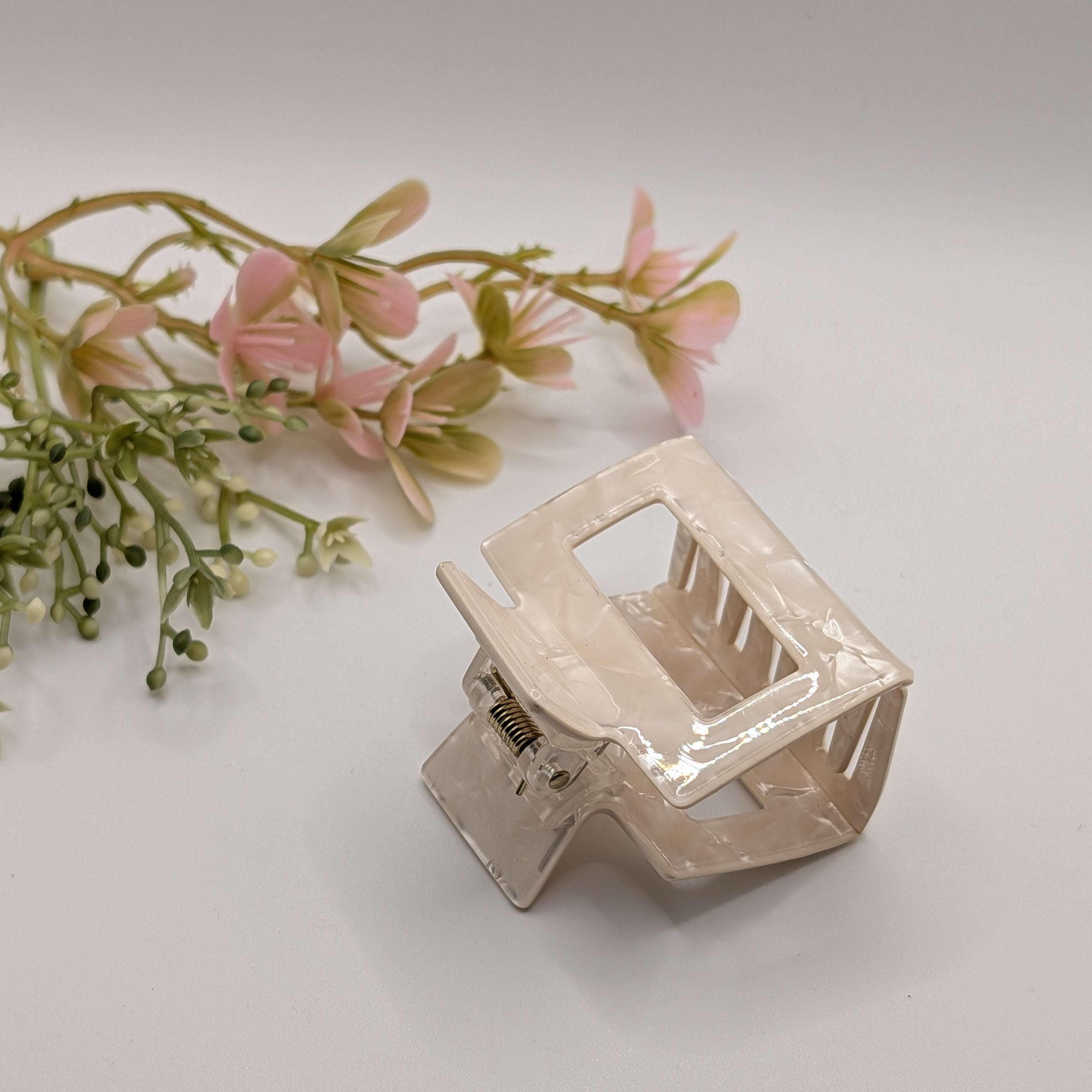 Creme Marmoriert - Haarspange „Classic Ivory“ | Perlmutt-Elfenbein - Mercy Haaraccessoires

Schrägansicht der cremeweißen Haarklammer mit Marmoreffekt neben rosa Dekorationsblumen.