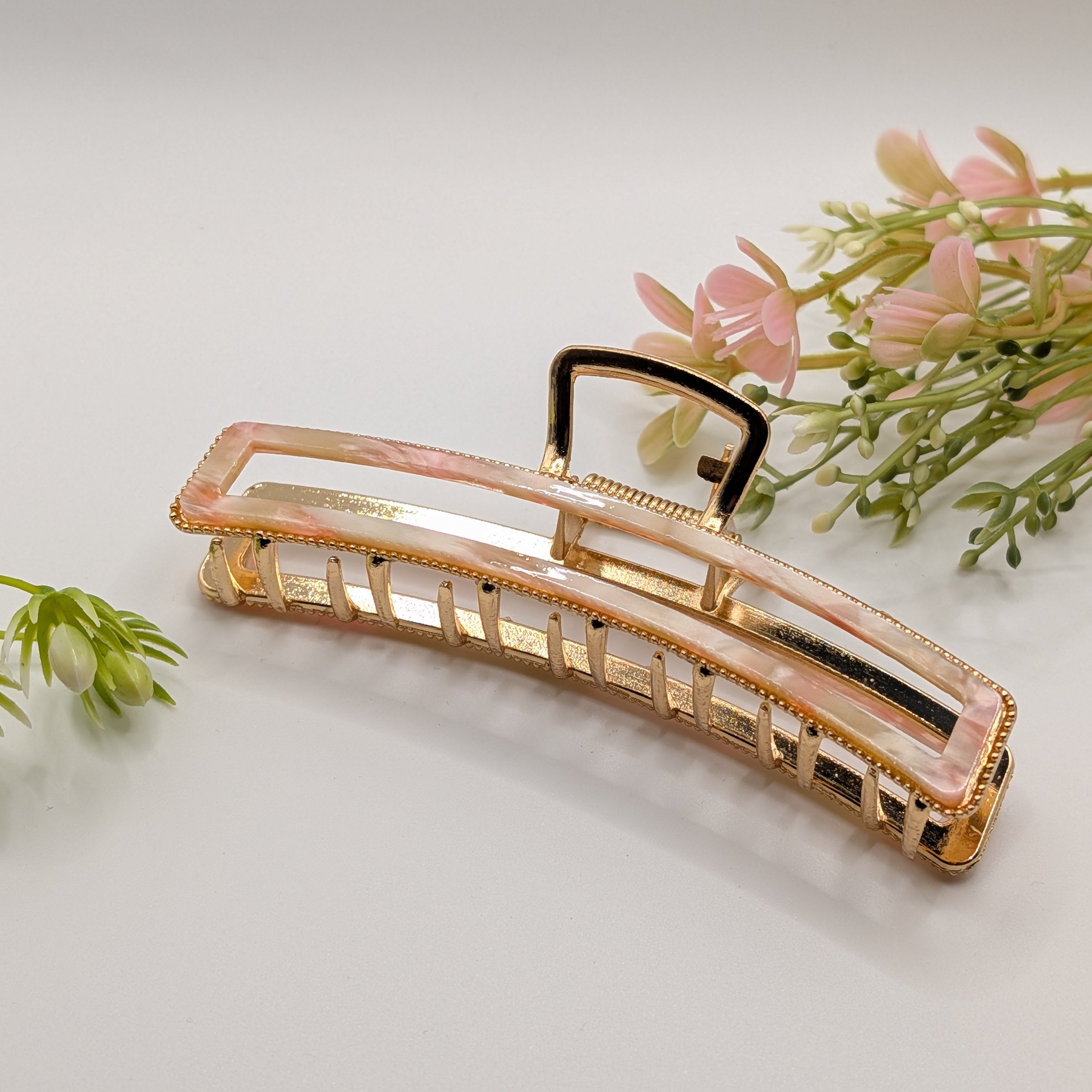 Rosa Marmor - "Metallic Pearl" 11cm Haarspange - Mercy Haaraccessoires

Elegante rechteckige Haarklammer in Gold mit rosa-weiß marmoriertem Inlay, flach liegend vor dekorativen rosa Blumen auf weißem Hintergrund.