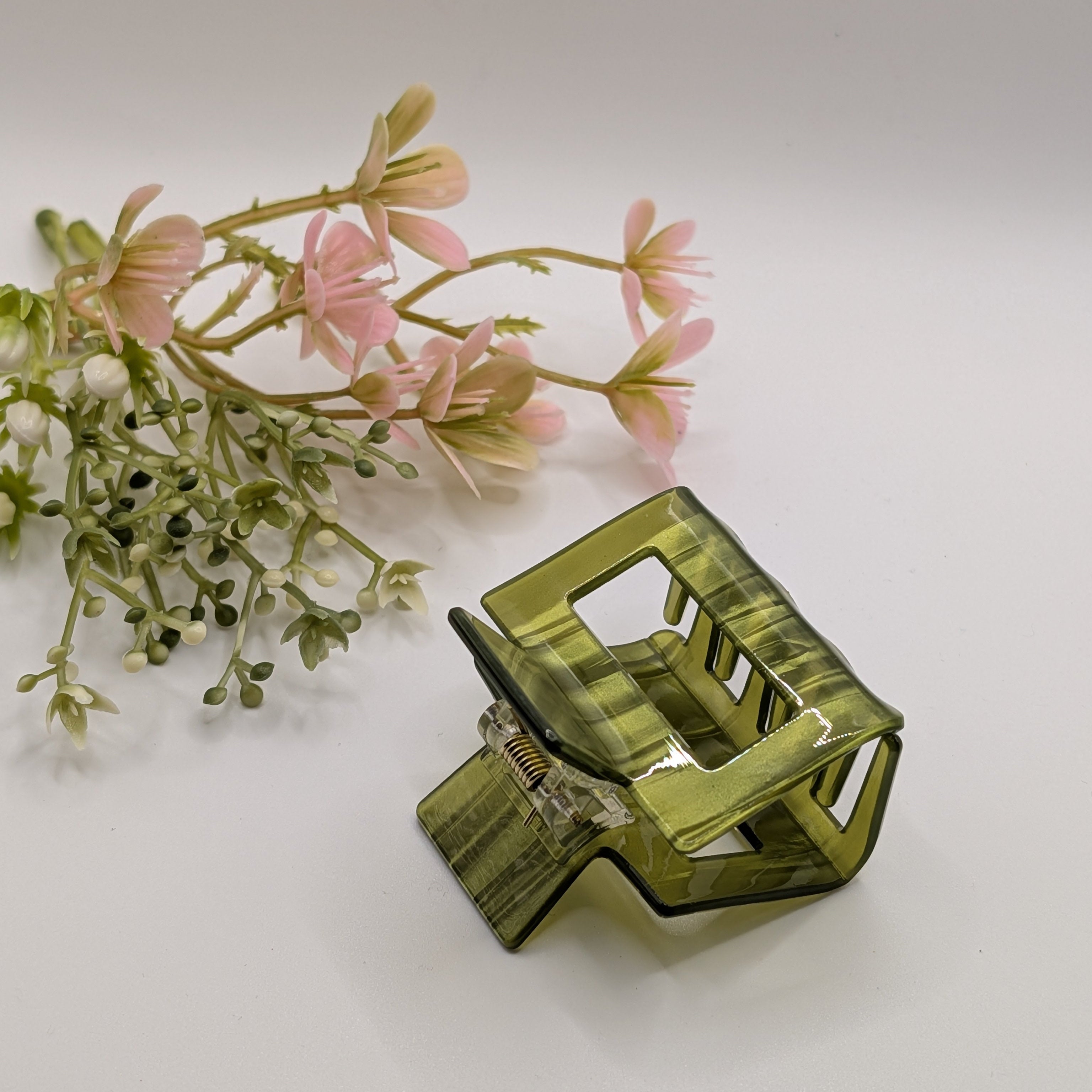 Olivgrün Gestreift - Kleine olivgrüne Haarklammer aus Acetat neben rosa Blumen, ideal als Haar-Accessoire für jeden Tag.