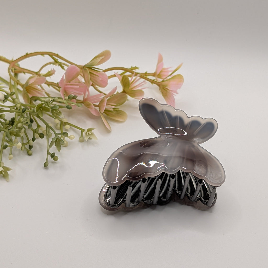 Geräucherter Obsidian - Haarspange „Smoky Night“ | Rauchgrau-Achat  - Mercy Haaraccessoires

Dunkelgrau marmorierte Schmetterlings-Haarklammer in der Seitenansicht neben rosa Kunstblumen.