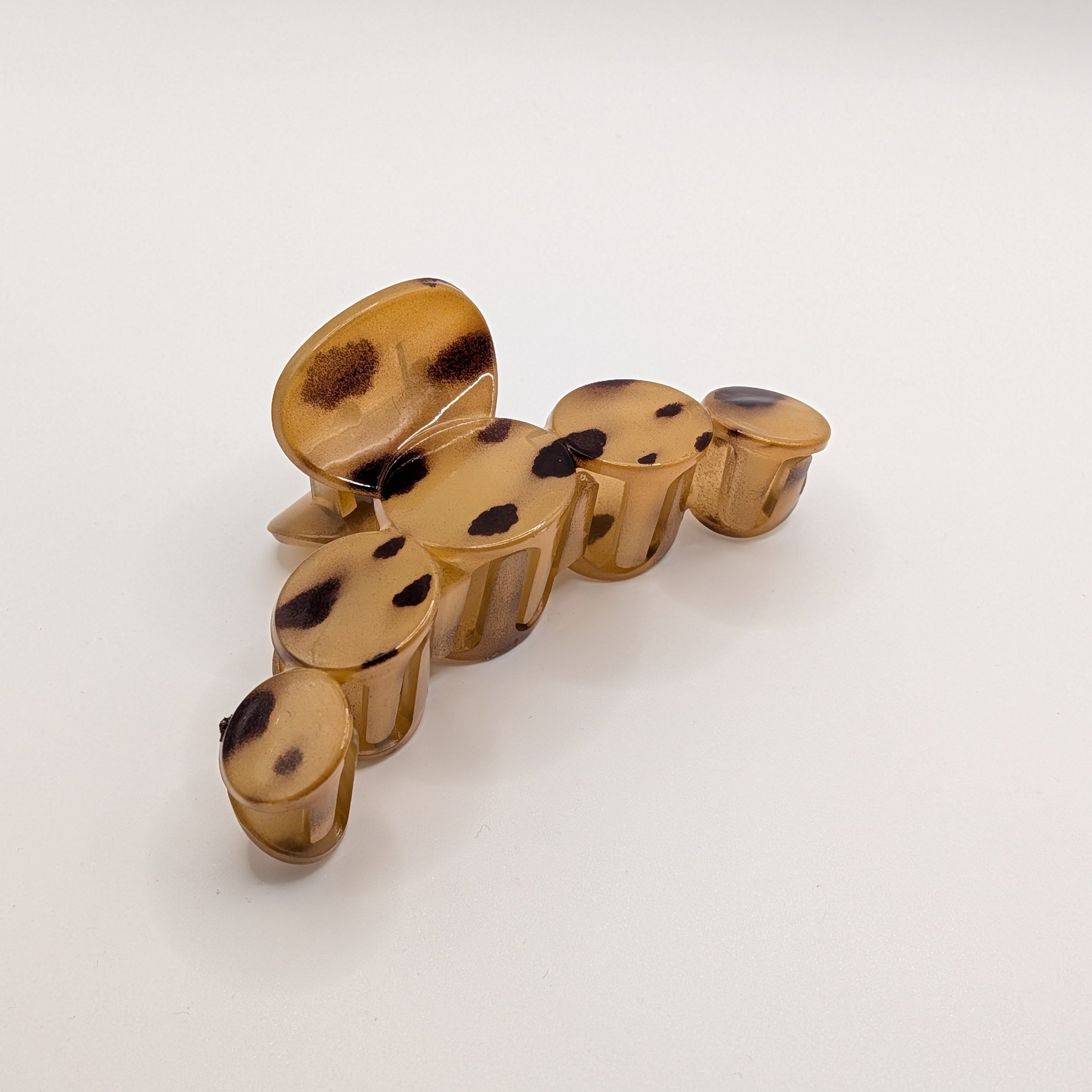 Hellbernstein Schildpatt - Angled side view of a large leopard print plastic hair claw showing the grip teeth.

Seitenansicht einer großen Haarklammer mit Leopardenmuster, die die Greifzähne zeigt.