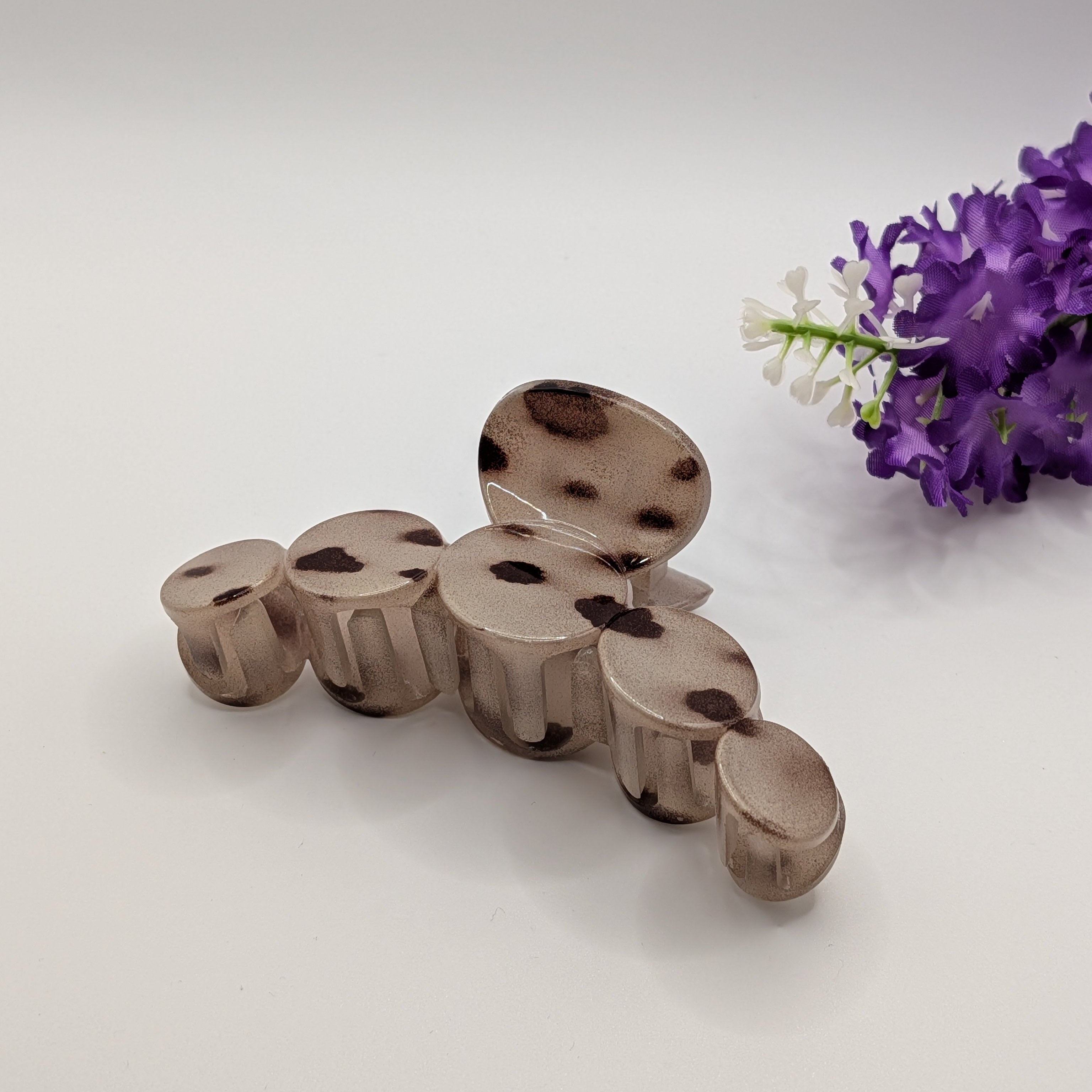 Cremiges Leopardenmuster - Smoky grey marble hair claw clip placed next to decorative purple flowers on a white background.

Rauchgraue Marmor-Haarklammer neben dekorativen lila Blumen auf weißem Hintergrund.