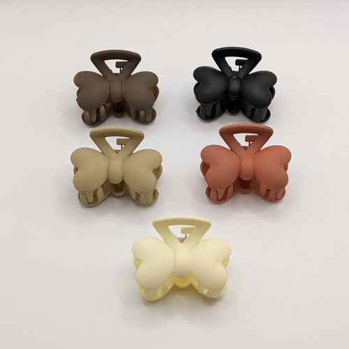Flat lay of five butterfly-shaped matte hair claw clips in black, brown, tan, terracotta, and cream.

5er-Set matte Schmetterlings-Haarklammern in Schwarz, Braun, Beige, Terrakotta und Creme.