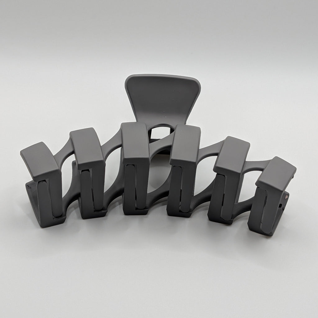 Grau - Front perspective view of a matte charcoal geometric hair claw clip showing its arched shape.	

Frontansicht einer matten, geometrischen XL-Haarklammer in Anthrazit, die die gewölbte Form zeigt.