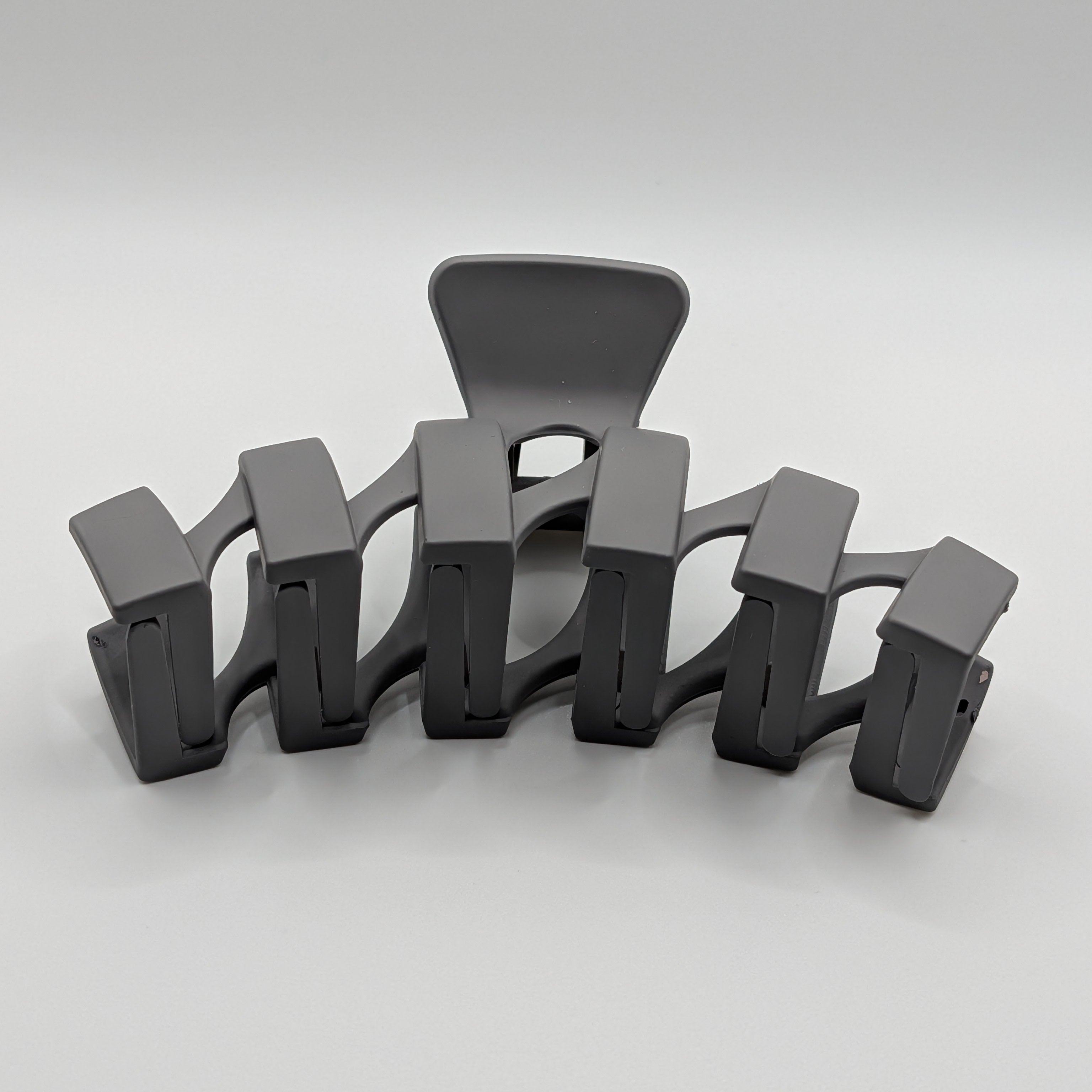 Grau - Front perspective view of a matte charcoal geometric hair claw clip showing its arched shape.	

Frontansicht einer matten, geometrischen XL-Haarklammer in Anthrazit, die die gewölbte Form zeigt.