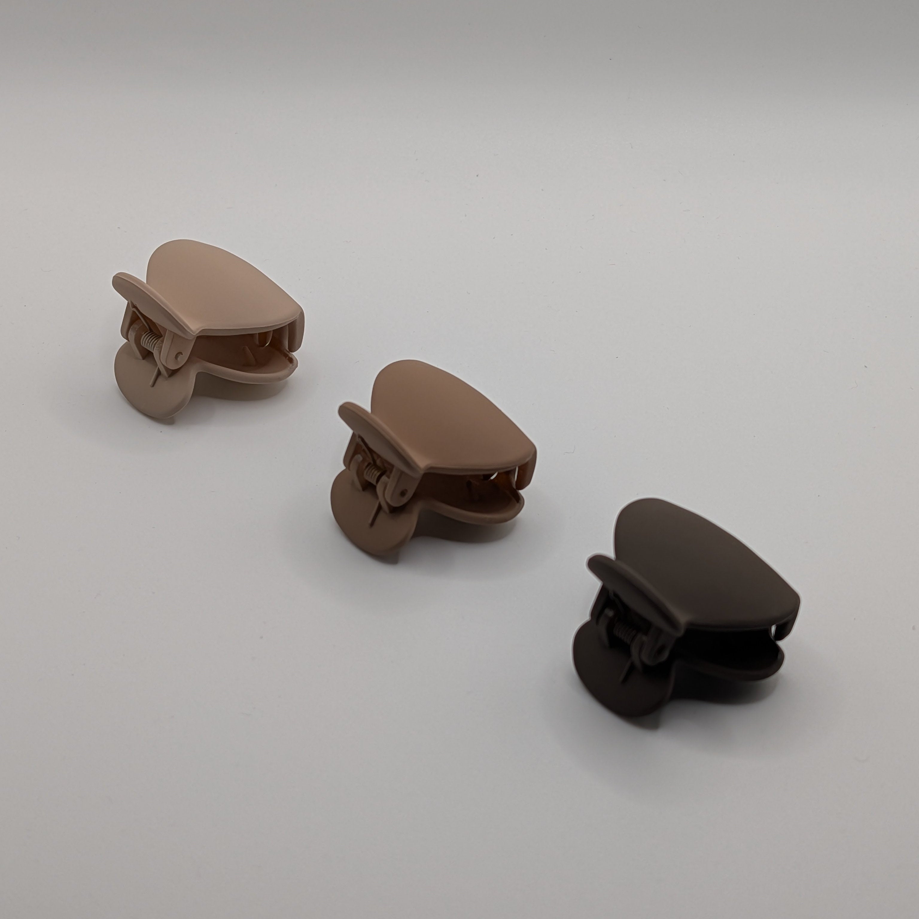 Three 4cm teardrop-shaped matte hair claw clips in neutral shades of beige and brown on a white background.

Drei 4cm tropfenförmige matte Haarklammern in neutralen Beige- und Brauntönen auf weißem Hintergrund.