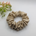 3er Set - Medium sized champagne gold satin scrunchie next to decorative flowers.

Mittelgroßes champagnerfarbenes Satin-Haargummi neben Blumen.