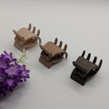 Three small 3cm matte hair claw clips in beige and brown shades next to purple flowers.

Drei kleine 3cm matte Haarklammern in Beige- und Brauntönen neben lila Blumen.