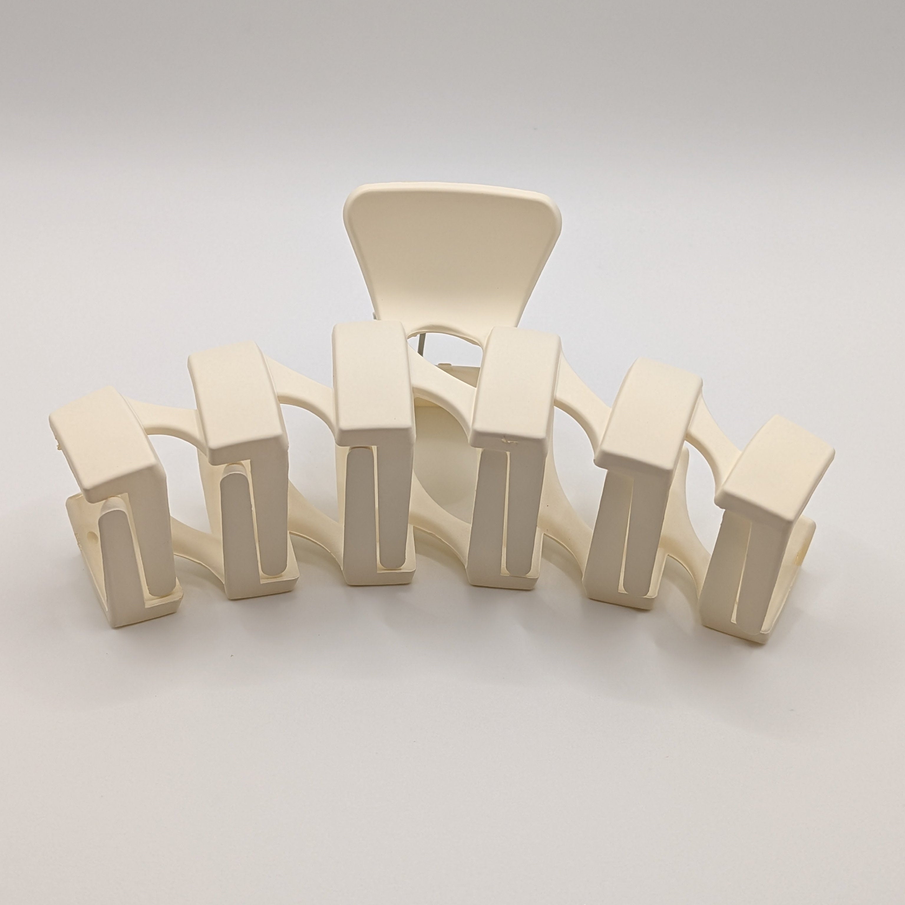 Creme - Front perspective of a modern cream-colored matte plastic hair claw for thick hair.

Frontalansicht einer modernen, cremefarbenen matten Haarklammer aus Kunststoff für dickes Haar.