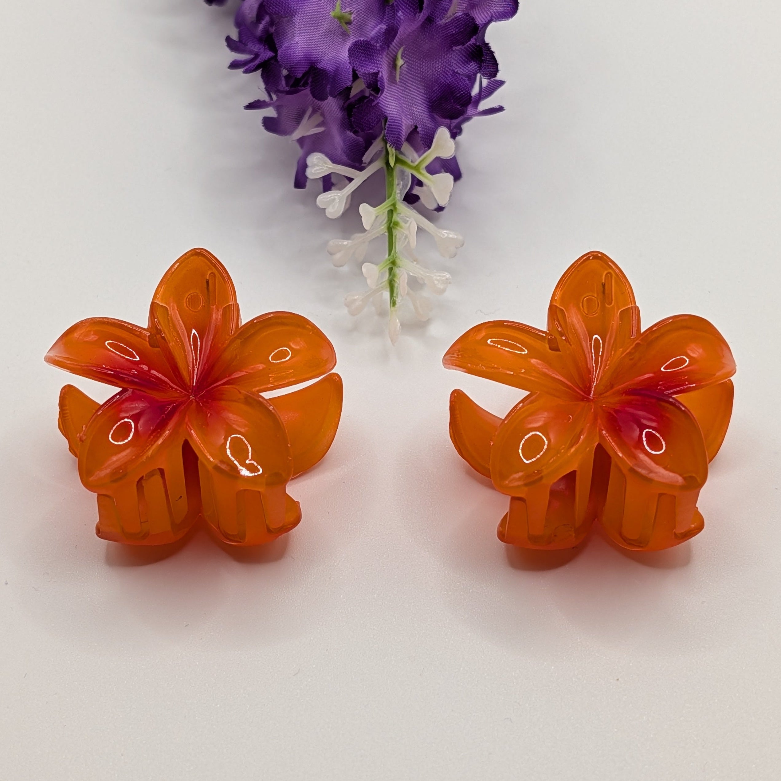 Leuchtendes Orange - Pair of orange flower hair clips with a purple floral sprig background.

Ein Paar orangefarbene Blumen-Haarclips vor einem Hintergrund mit lila Blumenzweig.