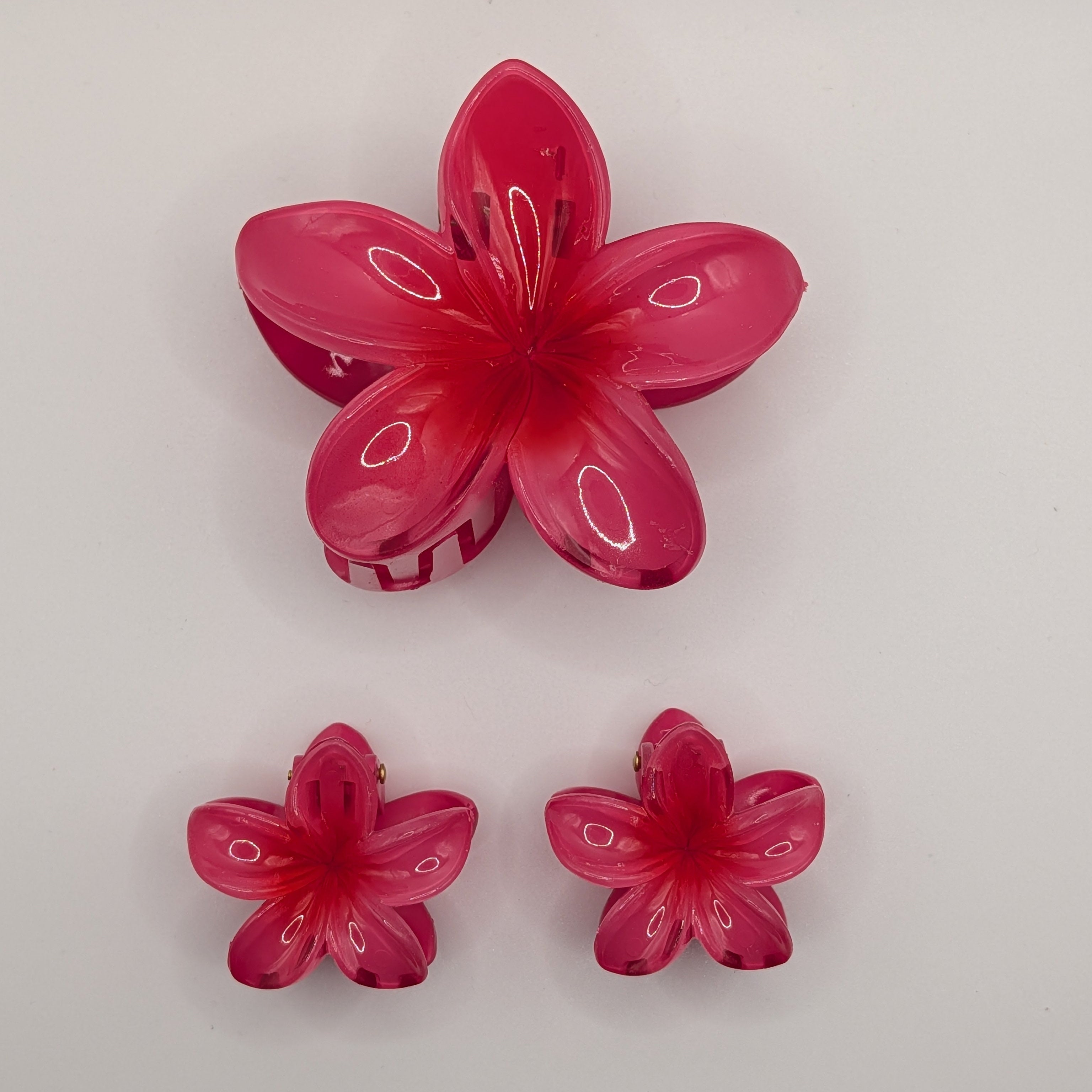 Fuchsiapink - Set of 3 pink plumeria flower hair claw clips (1 medium, 2 small) on white background.

3er-Set rosa Plumeria-Blüten-Haarklammern (1 mittel, 2 klein) auf weißem Hintergrund.
