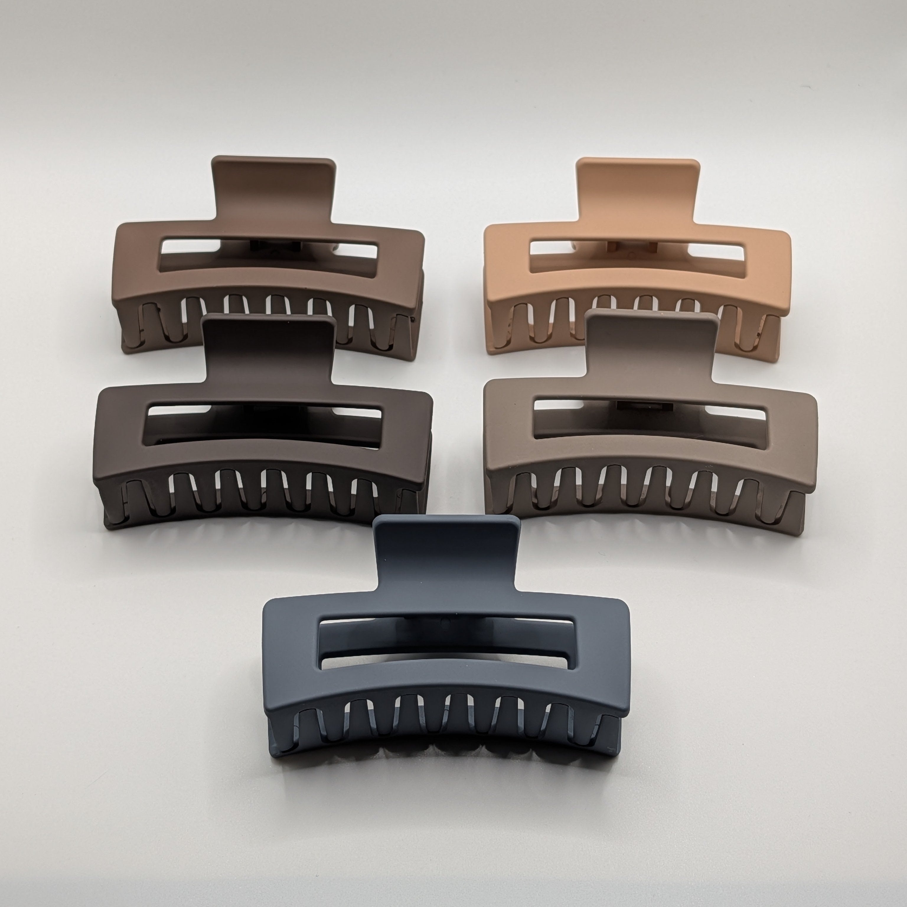 Front view of five 8cm strong-hold rectangular hair claw clips in shades of blue, brown, and tan.

Frontansicht von fünf 8 cm starken, rechteckigen Haarklammern in Blau-, Braun- und Beigetönen.