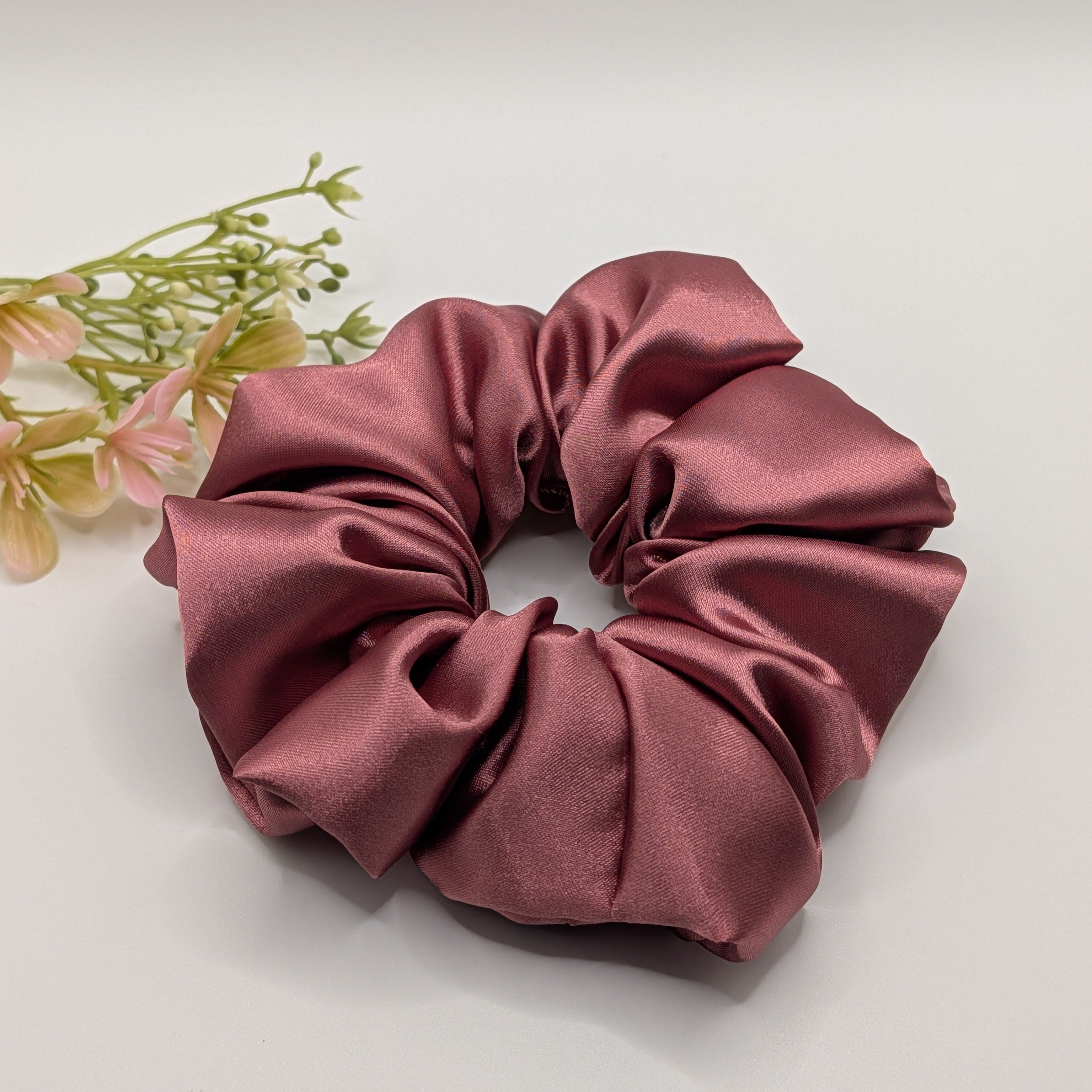 "3er-Set Dusty Rose" Satin-Scrunchie - Mercy Haaraccessoires

Ein extra großes Scrunchie aus luxuriösem mauvefarbenem Satin mit seidigem Glanz neben floraler Dekoration.