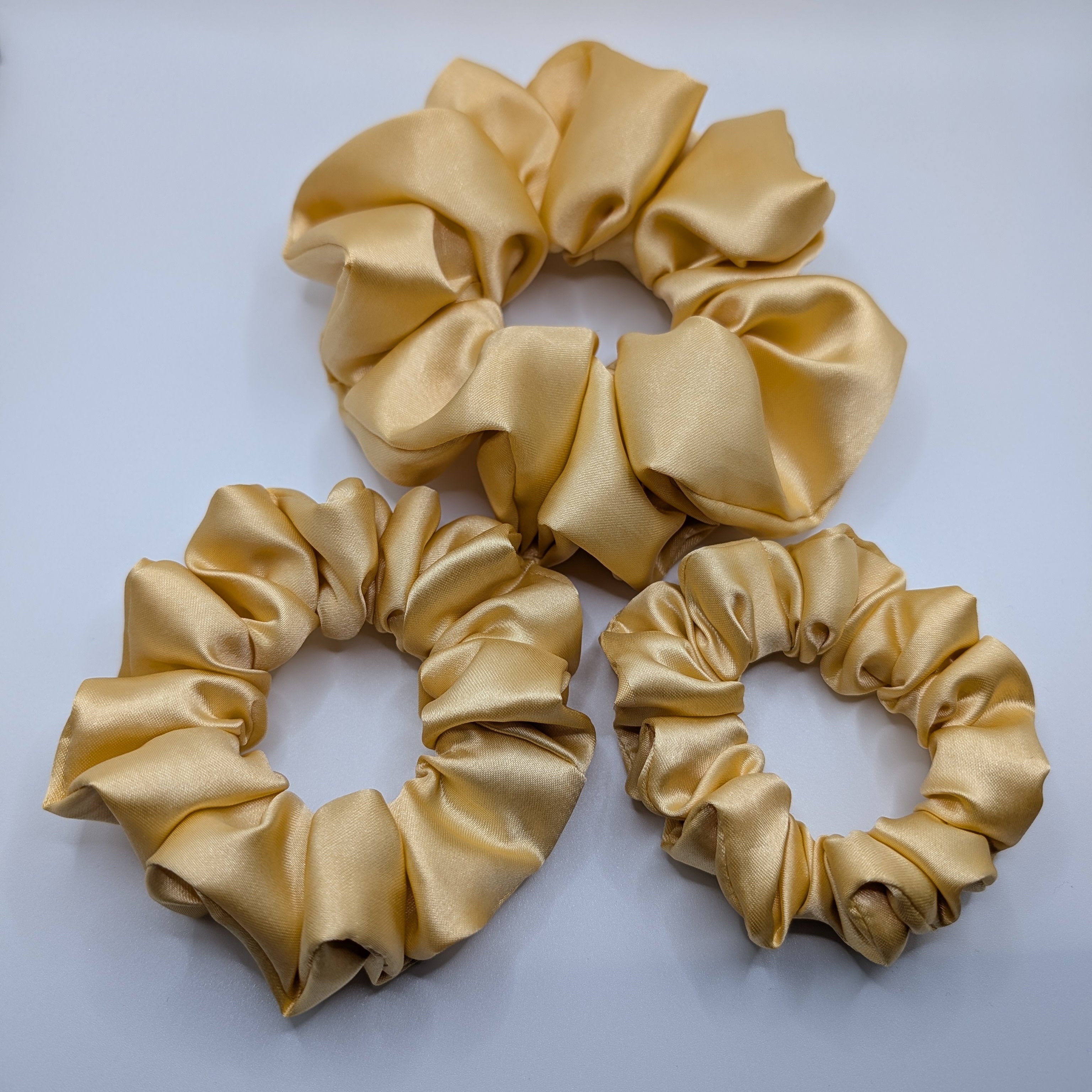 "3er-Set Champagne Glow" Satin-Scrunchie - Mercy Haaraccessoires

Ein 3er-Set goldfarbener Satin-Scrunchies in den Größen Groß, Mittel und Klein für vielseitige Looks.