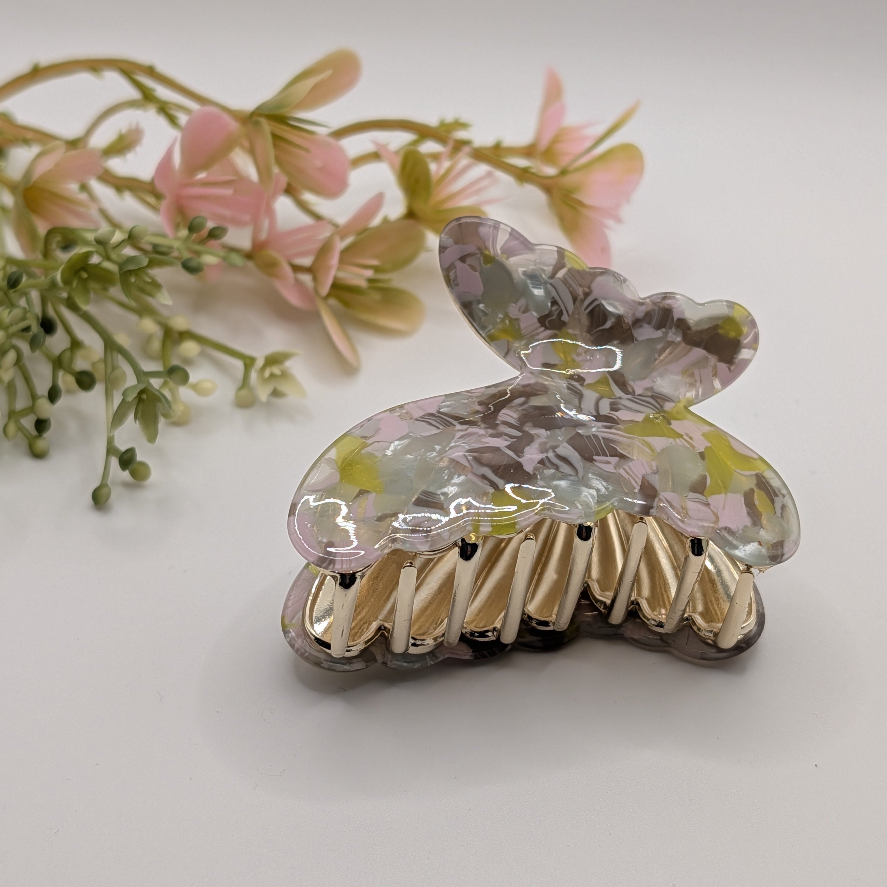 Gartenmoos Marmoriert - "Butterfly Garden" 6cm Haarspange

Elegante Haarklammer in Schmetterlingsform mit buntem Perlmutt-Muster und Gold-Details, Draufsicht.