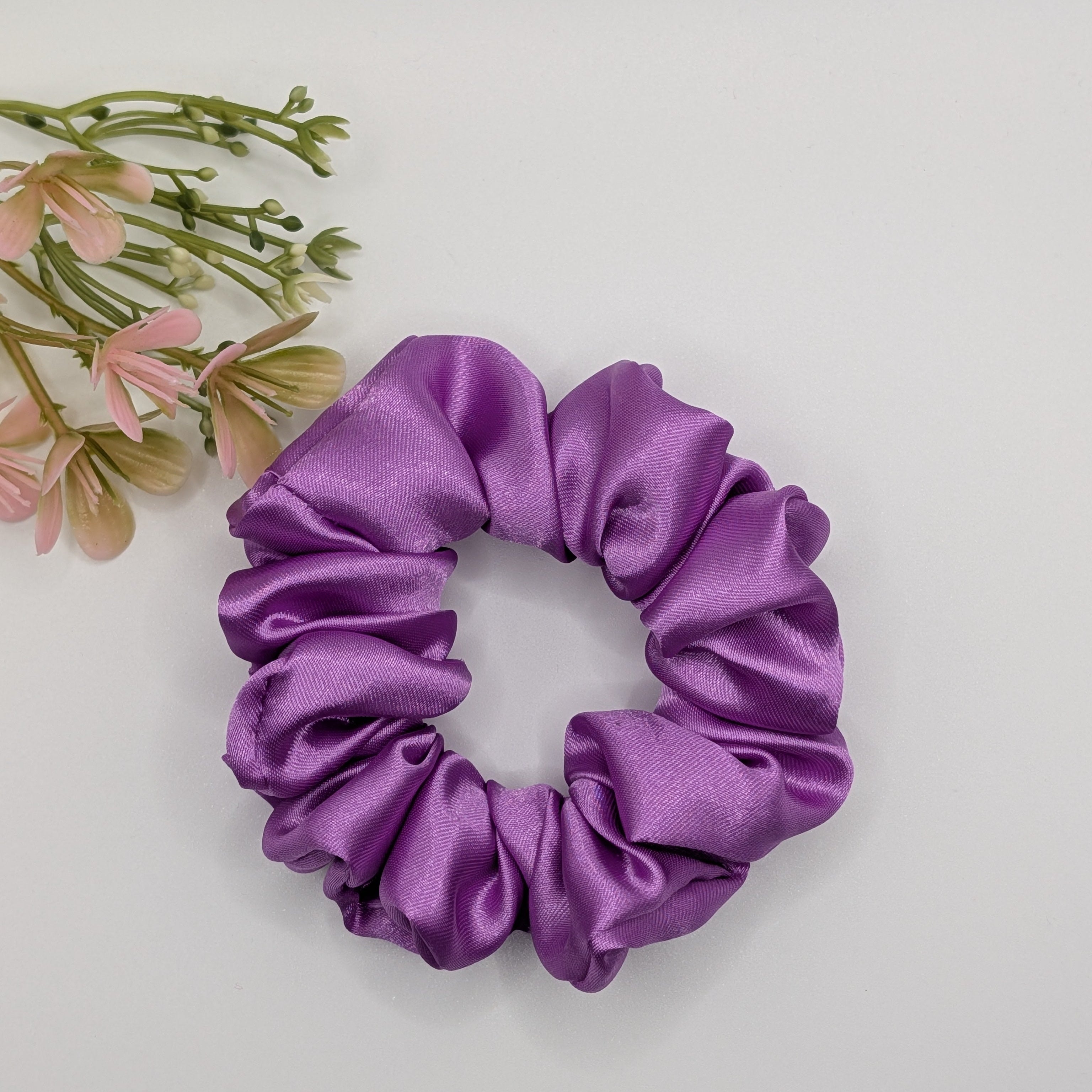 "Royal Amethyst" Satin-Scrunchie - Mercy Haaraccessoires

Ein mittelgroßes Haargummi aus violettem Satin mit feiner Raffung, präsentiert auf einer weißen Oberfläche mit floralem Akzent.