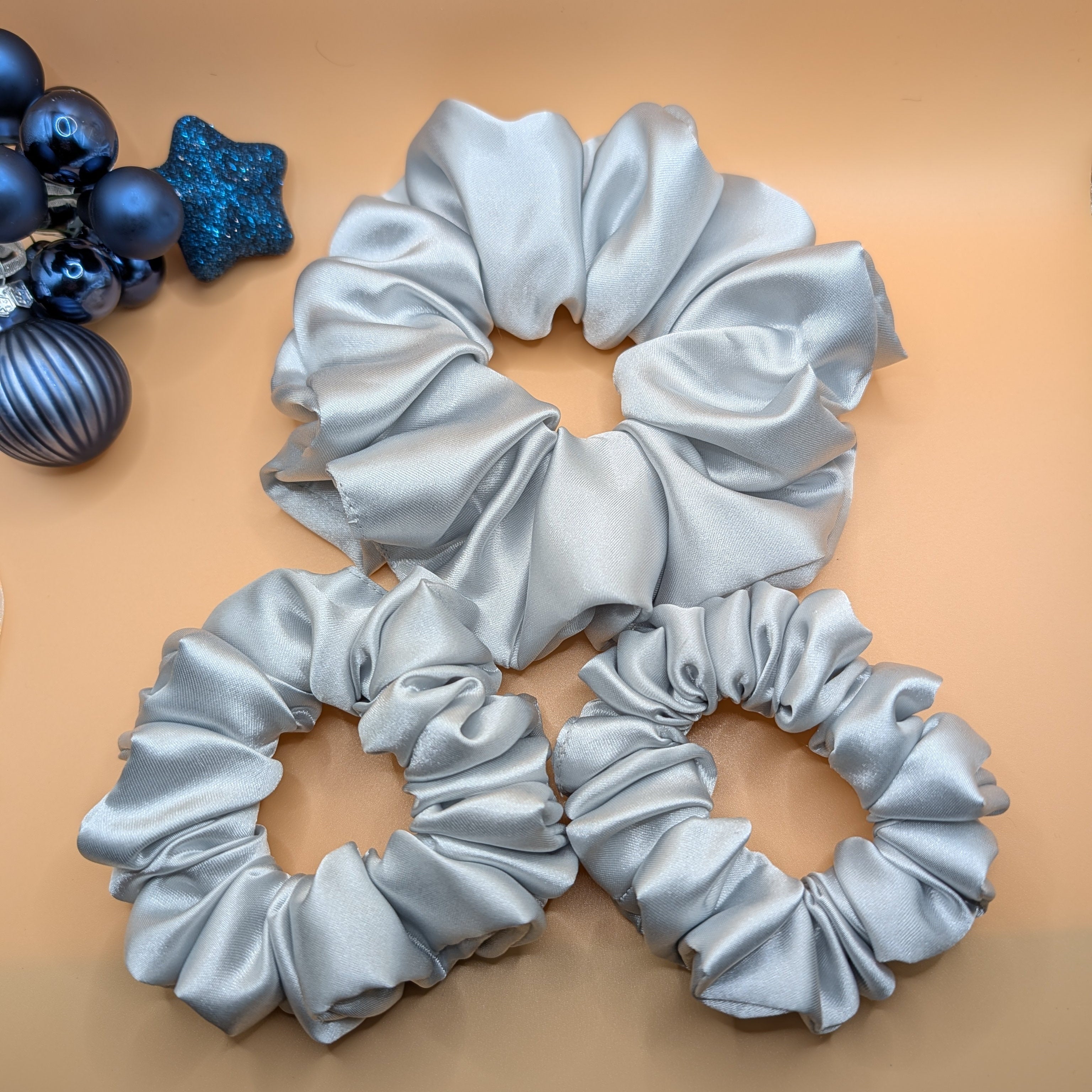 3er Set - Full 3-piece set of silver satin scrunchies in large, medium, and small sizes.

Komplettes 3-teiliges silbernes Satin-Scrunchie-Set in den Größen Groß, Mittel und Klein.