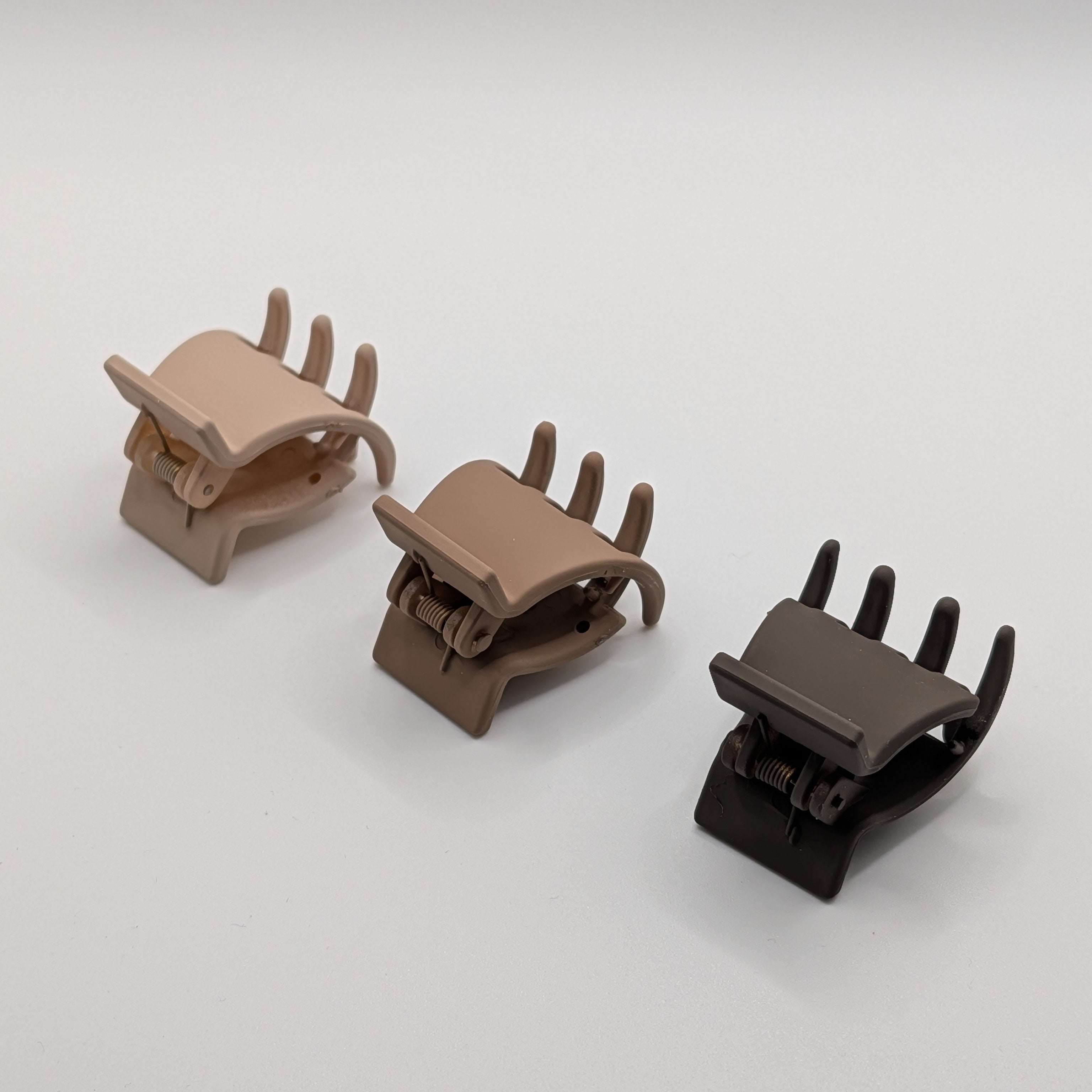 Side view of three 3cm mini hair claw clips in neutral earth tones on a white background.

Seitenansicht von drei 3cm Mini-Haarklammern in neutralen Erdtönen auf weißem Hintergrund.